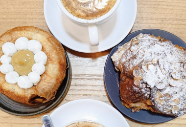 Colazione con cappuccino, croissant alle mandorle e sfogliato moderno con crema e chantilly